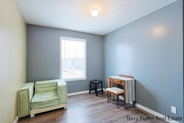 sitting room with a textured ceiling and wood-type flooring