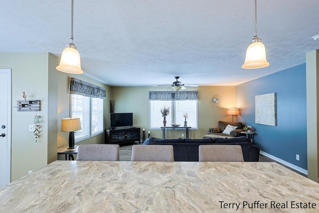 kitchen featuring a textured ceiling, ceiling fan, and hanging light fixtures