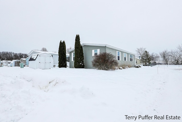 view of snowy exterior with a shed