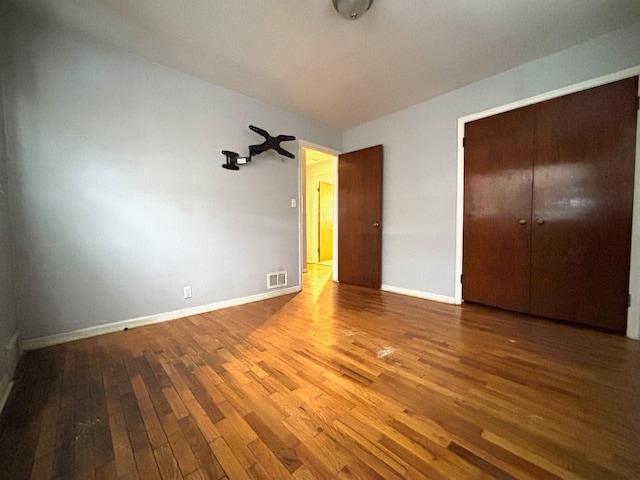 unfurnished bedroom with a closet and hardwood / wood-style flooring