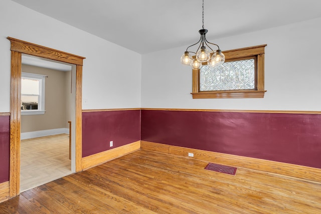 unfurnished room featuring a chandelier and hardwood / wood-style flooring