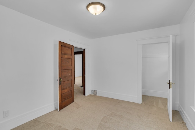 unfurnished bedroom featuring a closet and light colored carpet