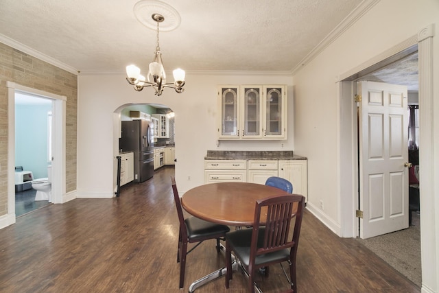 416 S Michigan Ave, Manton, MI 49663 - dining room with arched walkways, a chandelier, dark wood-type flooring, crown molding, and baseboards