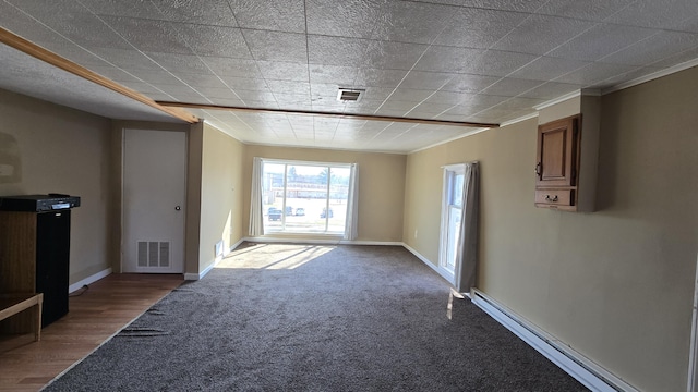 416 S Michigan Ave, Manton, MI 49663 - unfurnished living room featuring baseboard heating, ornamental molding, carpet, and baseboards