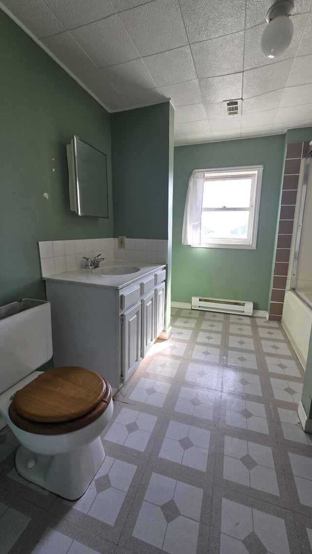 416 S Michigan Ave, Manton, MI 49663 - full bathroom with tile patterned floors, a baseboard heating unit, toilet, vanity, and baseboards