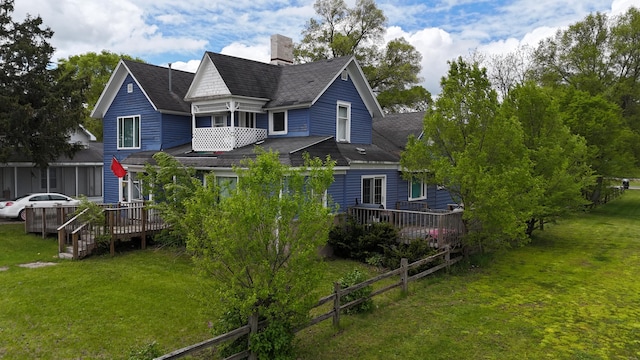 416 S Michigan Ave, Manton, MI 49663 - rear view of property featuring a chimney, a wooden deck, roof with shingles, and a lawn