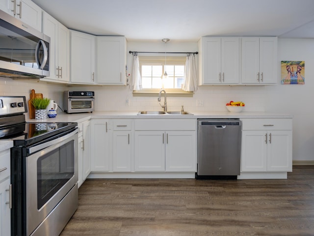 kitchen with stainless steel appliances, dark wood-type flooring, sink, white cabinetry, and backsplash