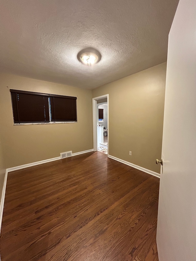 empty room featuring dark hardwood / wood-style flooring and a textured ceiling