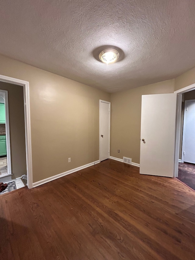 unfurnished room featuring a textured ceiling and dark wood-type flooring