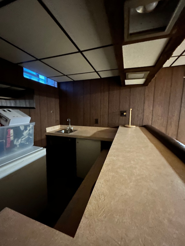 bar featuring a drop ceiling, wooden walls, and sink