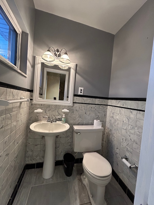 bathroom with tile walls, tile patterned flooring, toilet, and sink