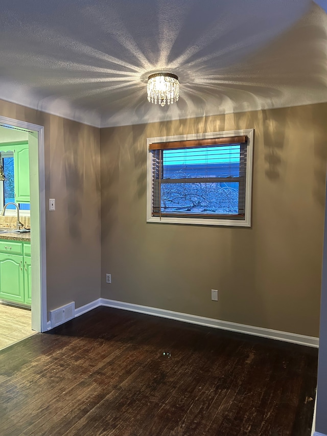 empty room featuring sink, a chandelier, and hardwood / wood-style flooring