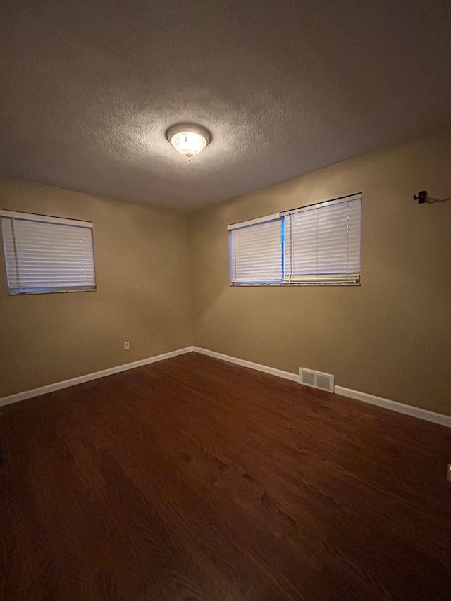 unfurnished room with dark wood-type flooring and a textured ceiling