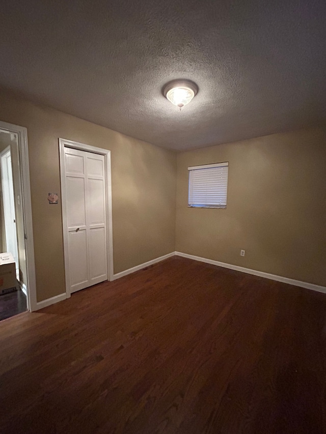 unfurnished bedroom with a closet, a textured ceiling, and dark wood-type flooring