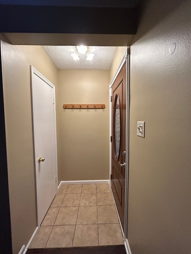 entryway featuring a textured ceiling, light tile patterned floors, and a chandelier