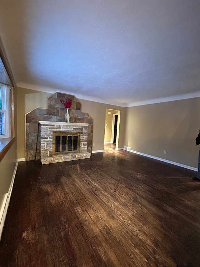 unfurnished living room with hardwood / wood-style floors and a stone fireplace