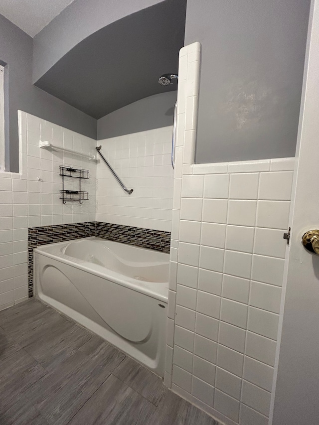 bathroom featuring shower / washtub combination, tile walls, and hardwood / wood-style floors