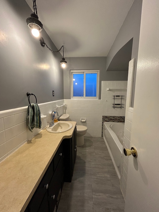 bathroom with tile walls, toilet, tile patterned floors, a tub, and vanity