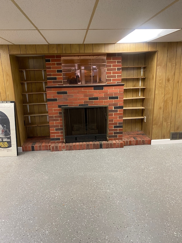 unfurnished living room with built in shelves, a fireplace, and wood walls