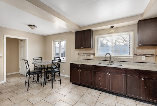 kitchen featuring sink, a healthy amount of sunlight, tasteful backsplash, and dark brown cabinets