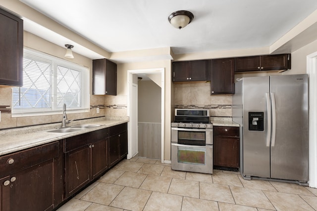 kitchen featuring appliances with stainless steel finishes, dark brown cabinetry, light tile patterned floors, and sink