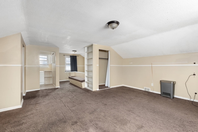 bonus room featuring dark carpet, a textured ceiling, and vaulted ceiling