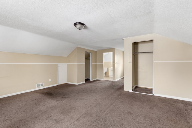 bonus room featuring dark carpet, a textured ceiling, and vaulted ceiling