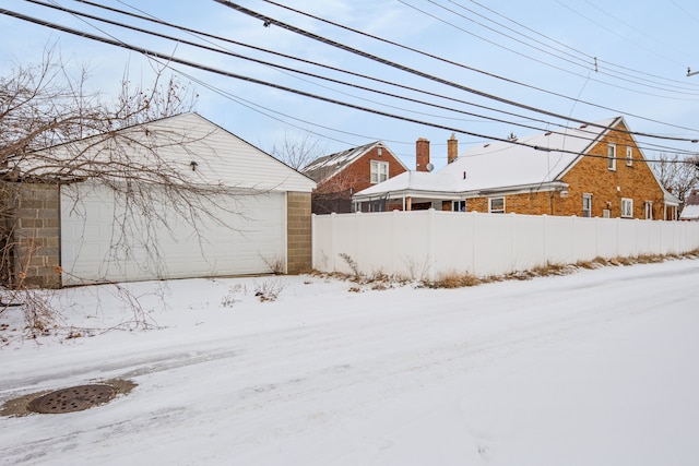 yard layered in snow with a garage and an outbuilding