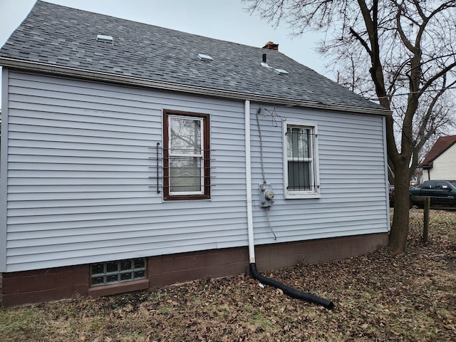 view of home's exterior with a shingled roof and a chimney