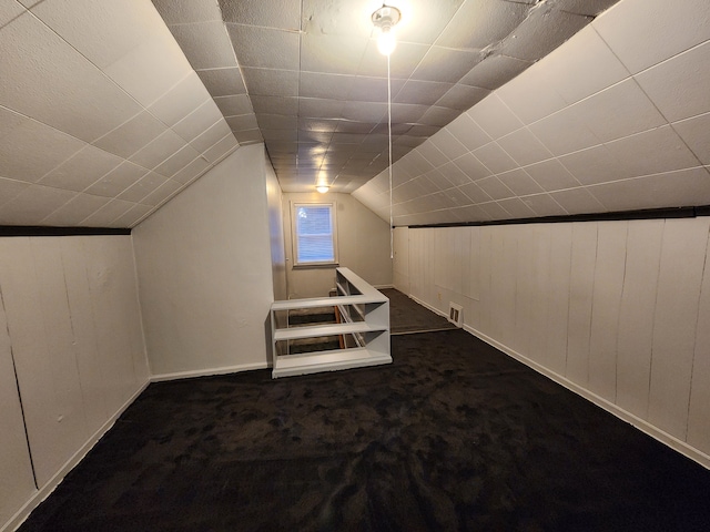 bonus room with vaulted ceiling, visible vents, and dark colored carpet