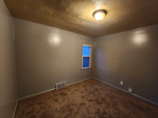 carpeted spare room with a textured ceiling, visible vents, and baseboards