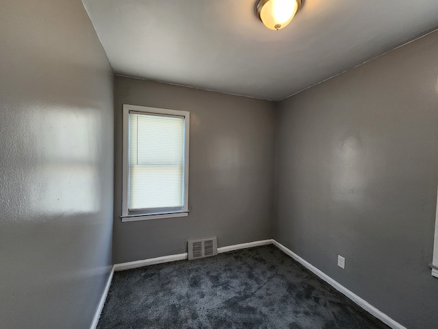 unfurnished room featuring dark colored carpet, visible vents, and baseboards