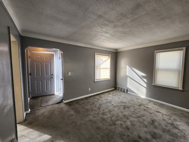 empty room featuring baseboards, a textured ceiling, visible vents, and carpet flooring