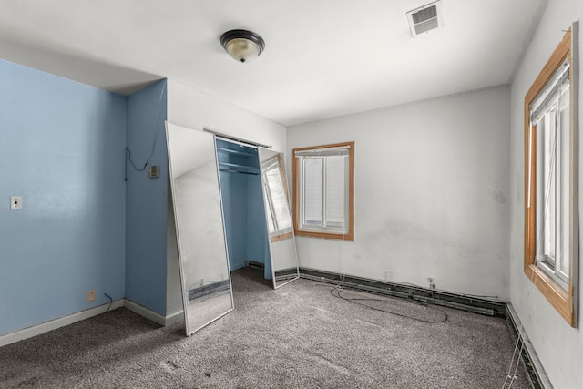 unfurnished bedroom featuring multiple windows, dark carpet, and a closet