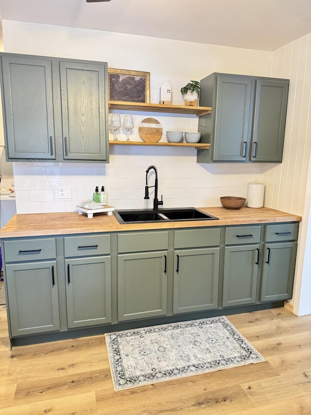 kitchen featuring light wood-type flooring, wood counters, tasteful backsplash, and sink