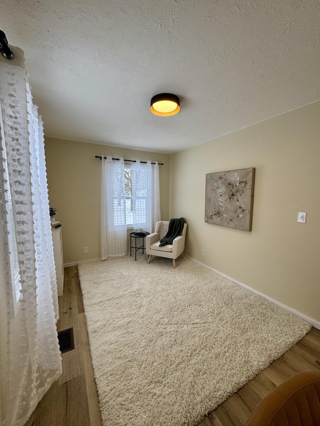 living area with wood-type flooring and a textured ceiling