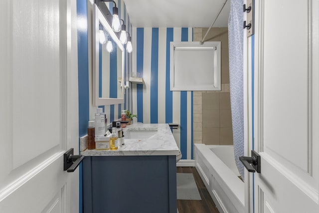 bathroom with hardwood / wood-style floors, tiled shower / bath combo, and vanity