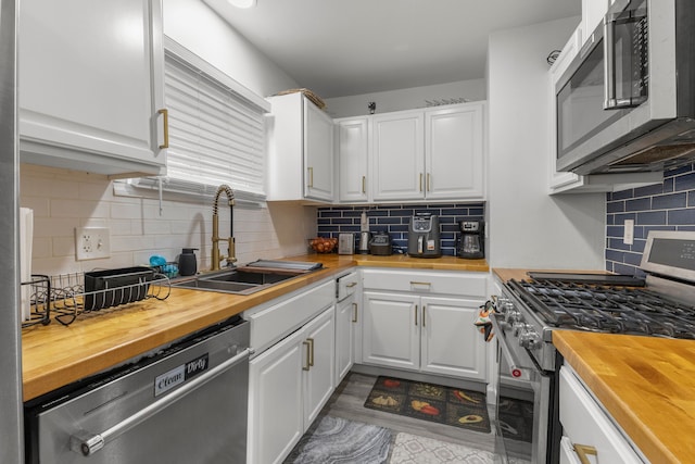 kitchen with sink, white cabinets, wood counters, and appliances with stainless steel finishes