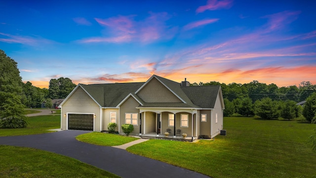 view of front of property featuring covered porch, a lawn, and a garage