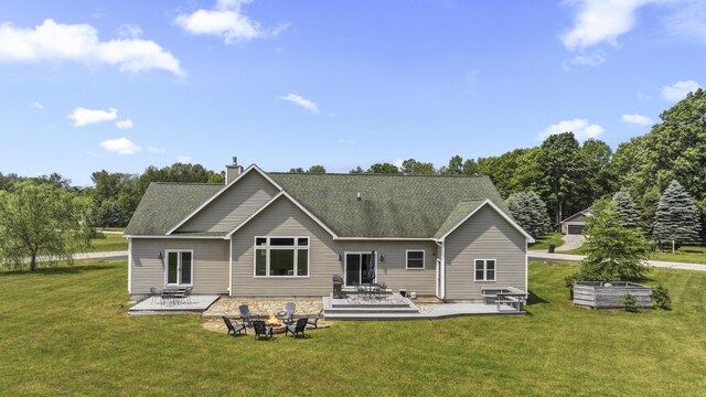 back of property with a fire pit, a patio, and a lawn