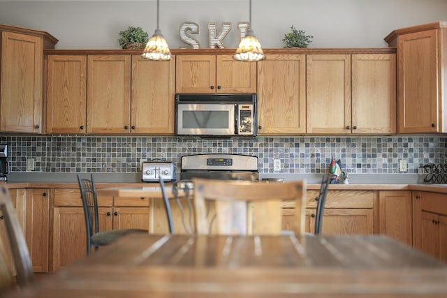 kitchen featuring appliances with stainless steel finishes, backsplash, and pendant lighting
