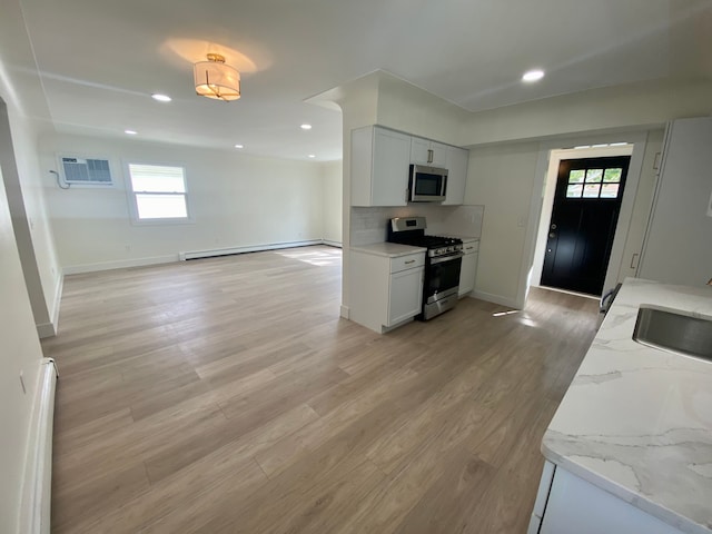 kitchen with white cabinetry, light stone countertops, baseboard heating, plenty of natural light, and appliances with stainless steel finishes