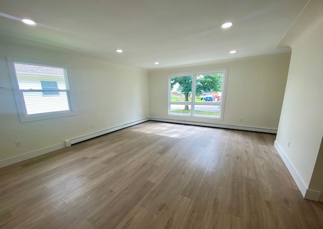 unfurnished room with baseboard heating and light wood-type flooring