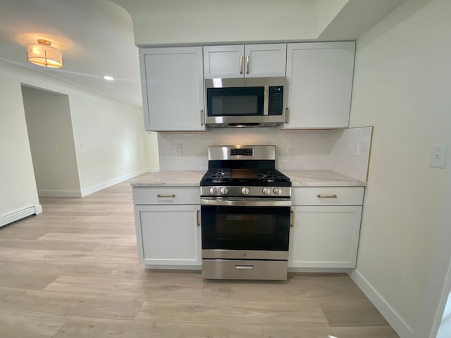 kitchen with white cabinets, appliances with stainless steel finishes, and backsplash