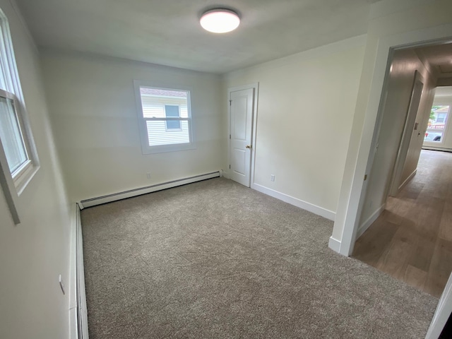 unfurnished room featuring a baseboard heating unit and carpet floors