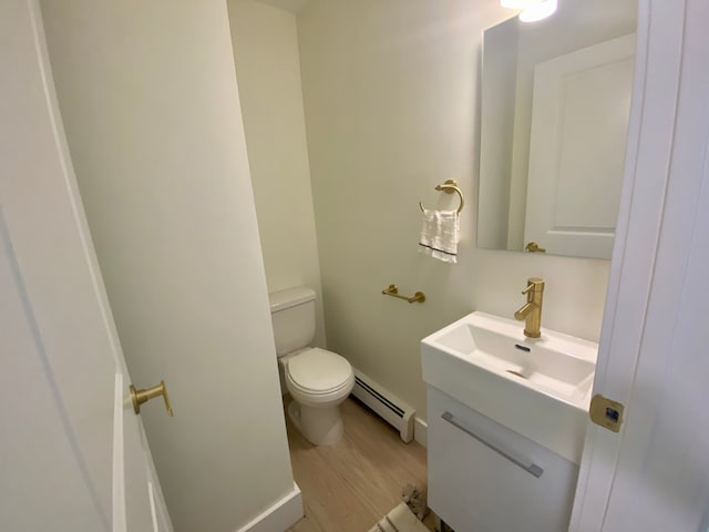 bathroom with toilet, vanity, baseboard heating, and hardwood / wood-style flooring