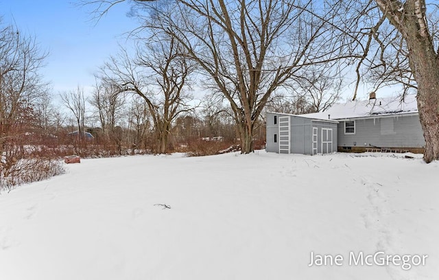 yard layered in snow with a storage shed