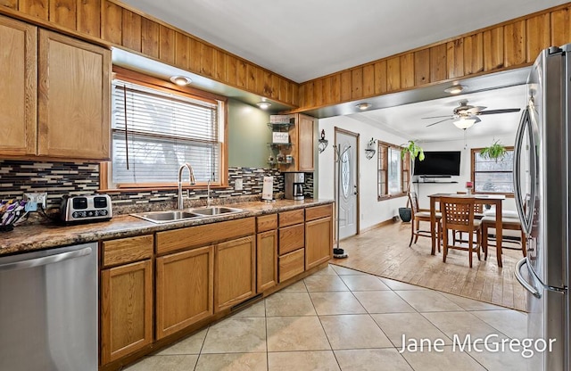 kitchen with stainless steel appliances, tasteful backsplash, light tile patterned flooring, ceiling fan, and sink