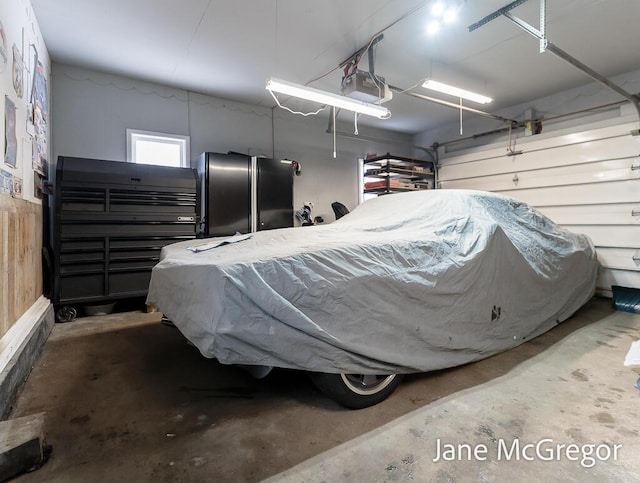 garage with stainless steel fridge and a garage door opener