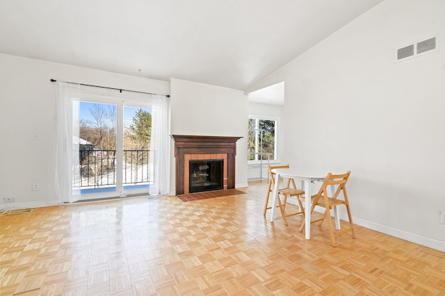 living room with vaulted ceiling, light parquet flooring, and a tiled fireplace